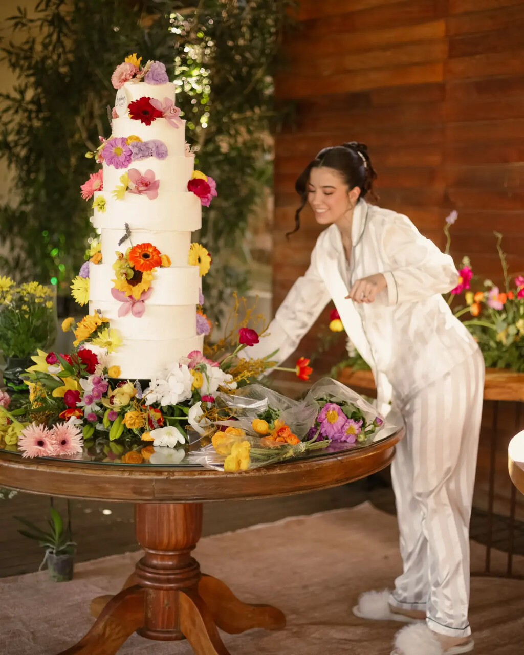 Luiza Dolce Della ao lado de um bolo de casamento decorado com flores